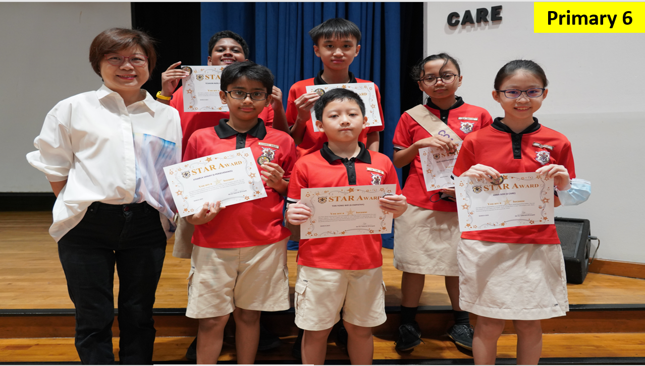 A teacher and six Primary 6 students in red uniforms pose on a stage holding Star Award certificates.